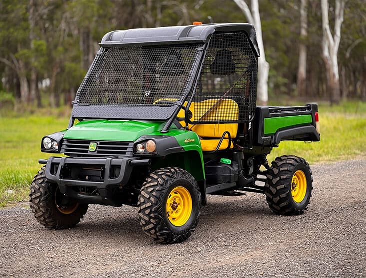 Utility vehicle with rugged tires and protective mesh windshield for farming and outdoor work.