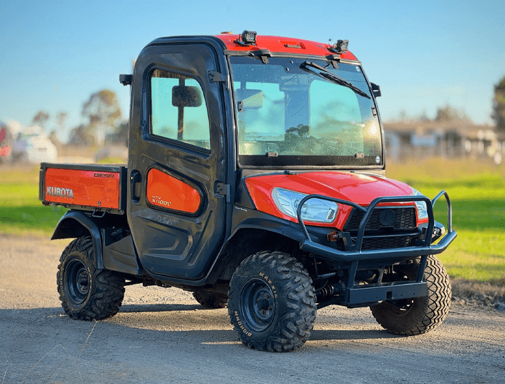 Utility vehicle with rugged tires and enclosed cabin, ideal for farming and construction tasks.